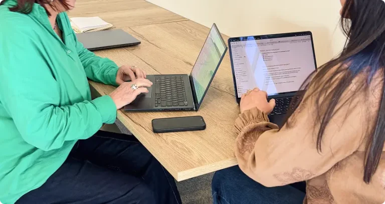Deux femmes discutent avec leur ordinateur sur une table de réunion